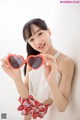 A young woman holding up a pair of heart shaped sunglasses.